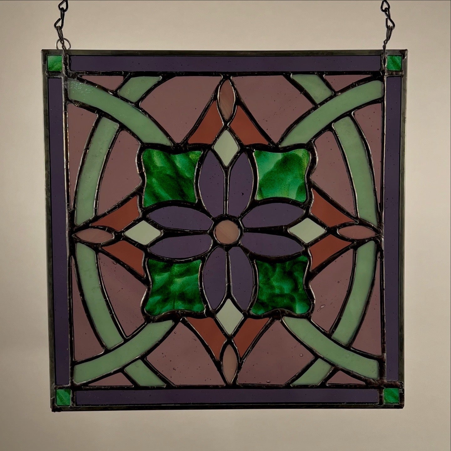 Stained glass panel with a purple flower design on a beige background