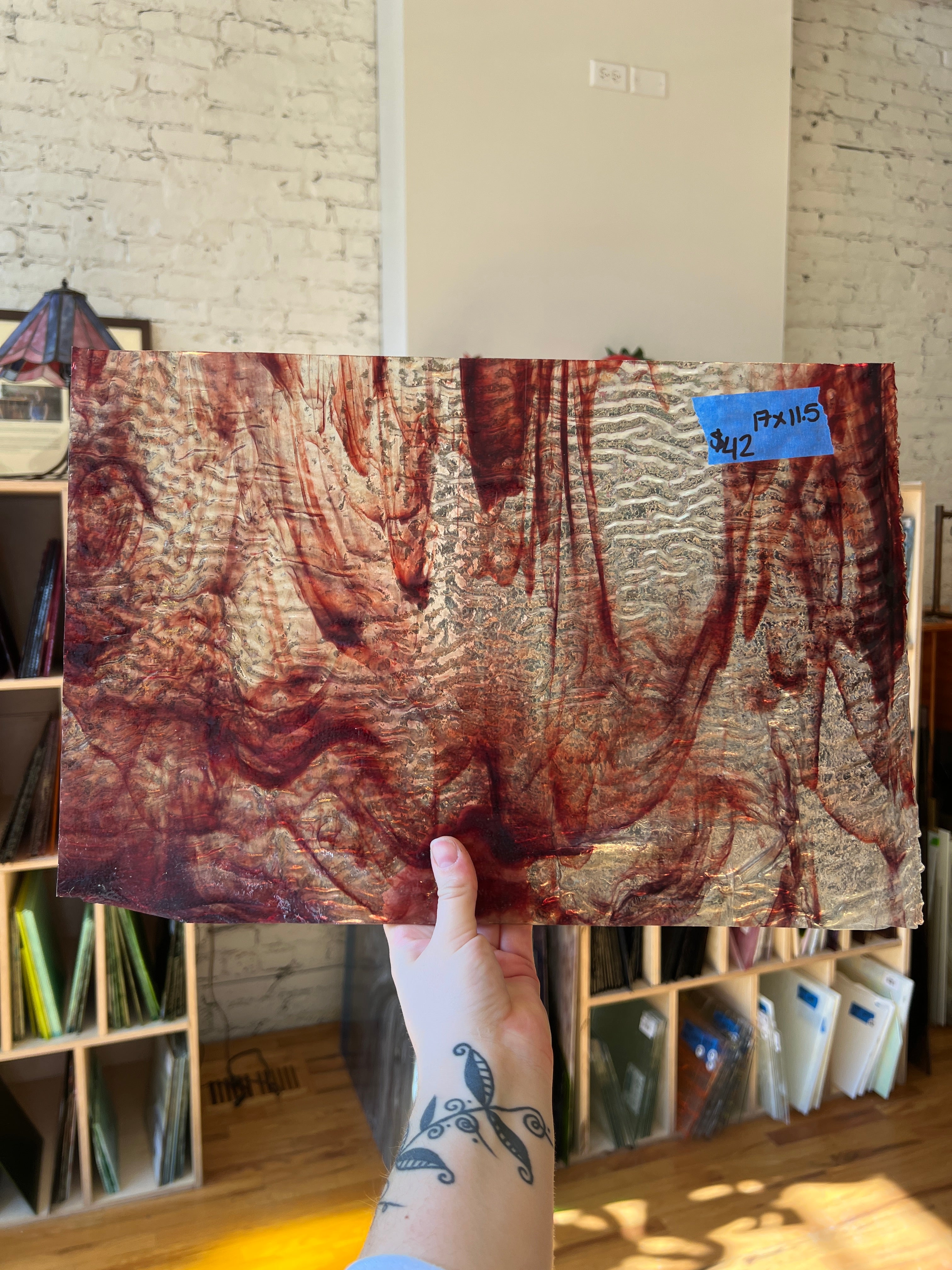 Hand holding a textured clear and red piece of glass with a blurred indoor background