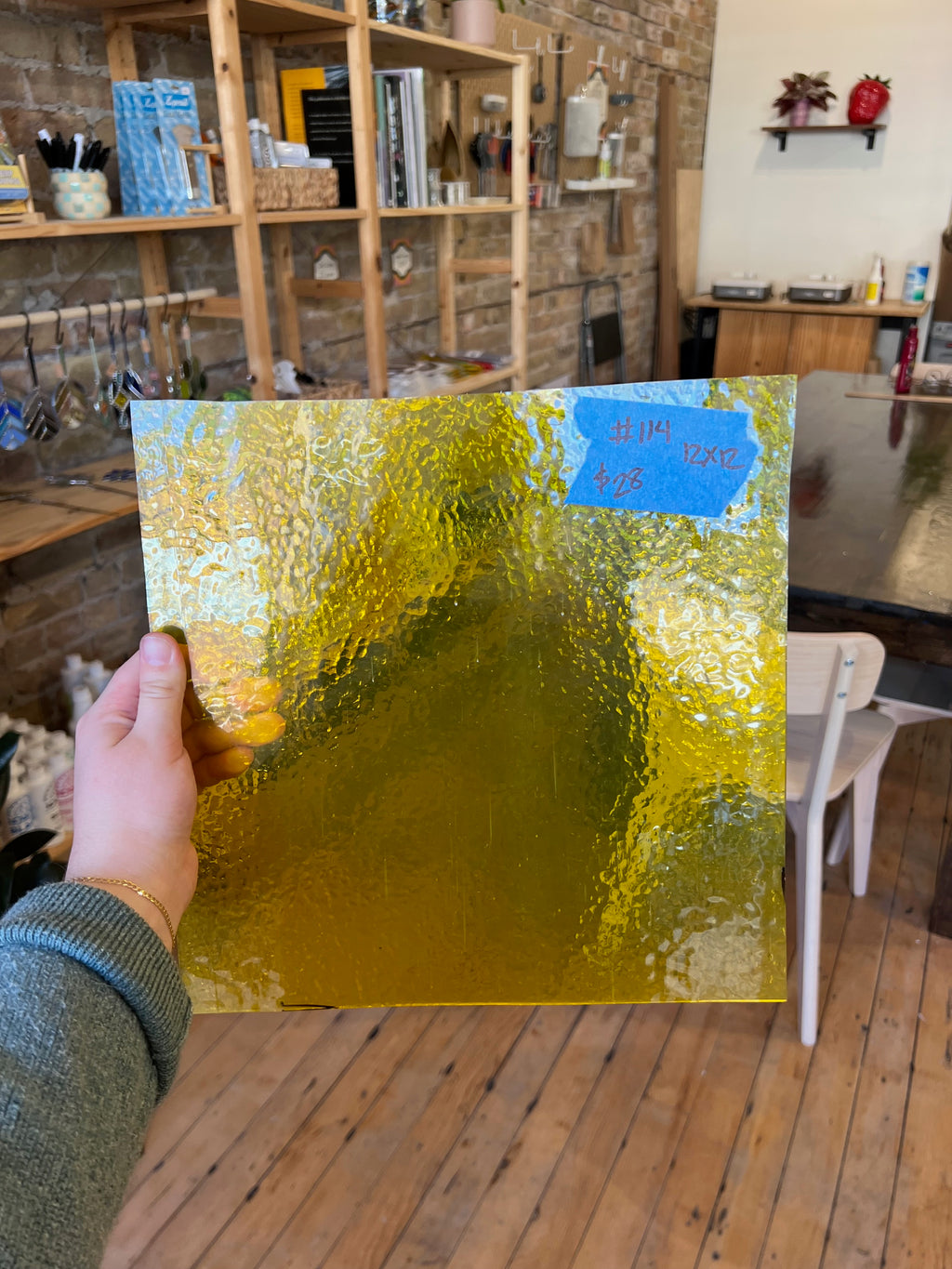 Hand holding a gold glass sheet with a blurred indoor background