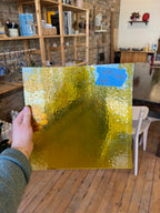 Hand holding a gold glass sheet with a blurred indoor background