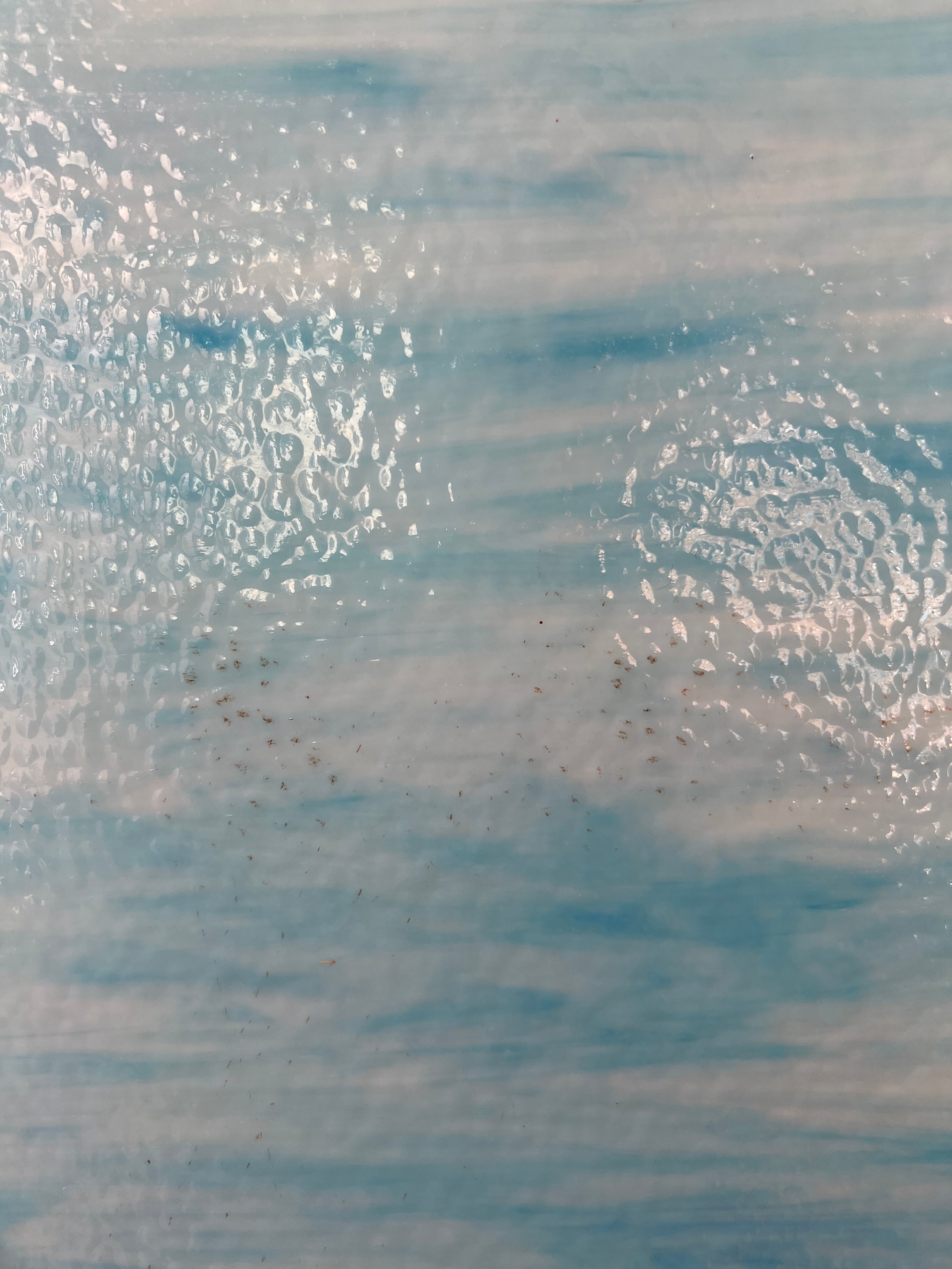Textured blue and white glass surface with small rust spots