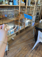 Person holding a reflective glass sheet with blurred indoor background
