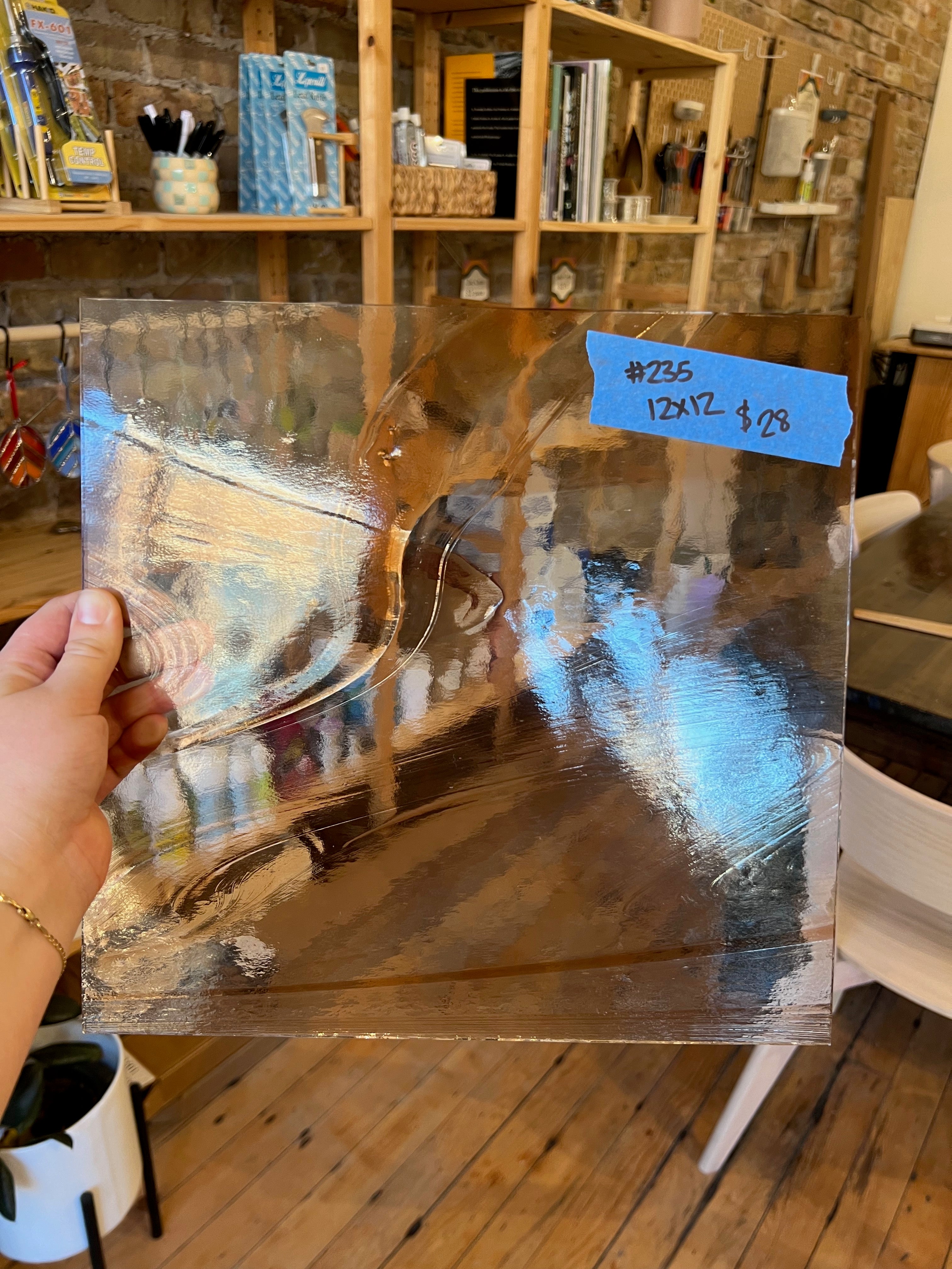 Person holding a large rectangular piece of glass in a store setting.
