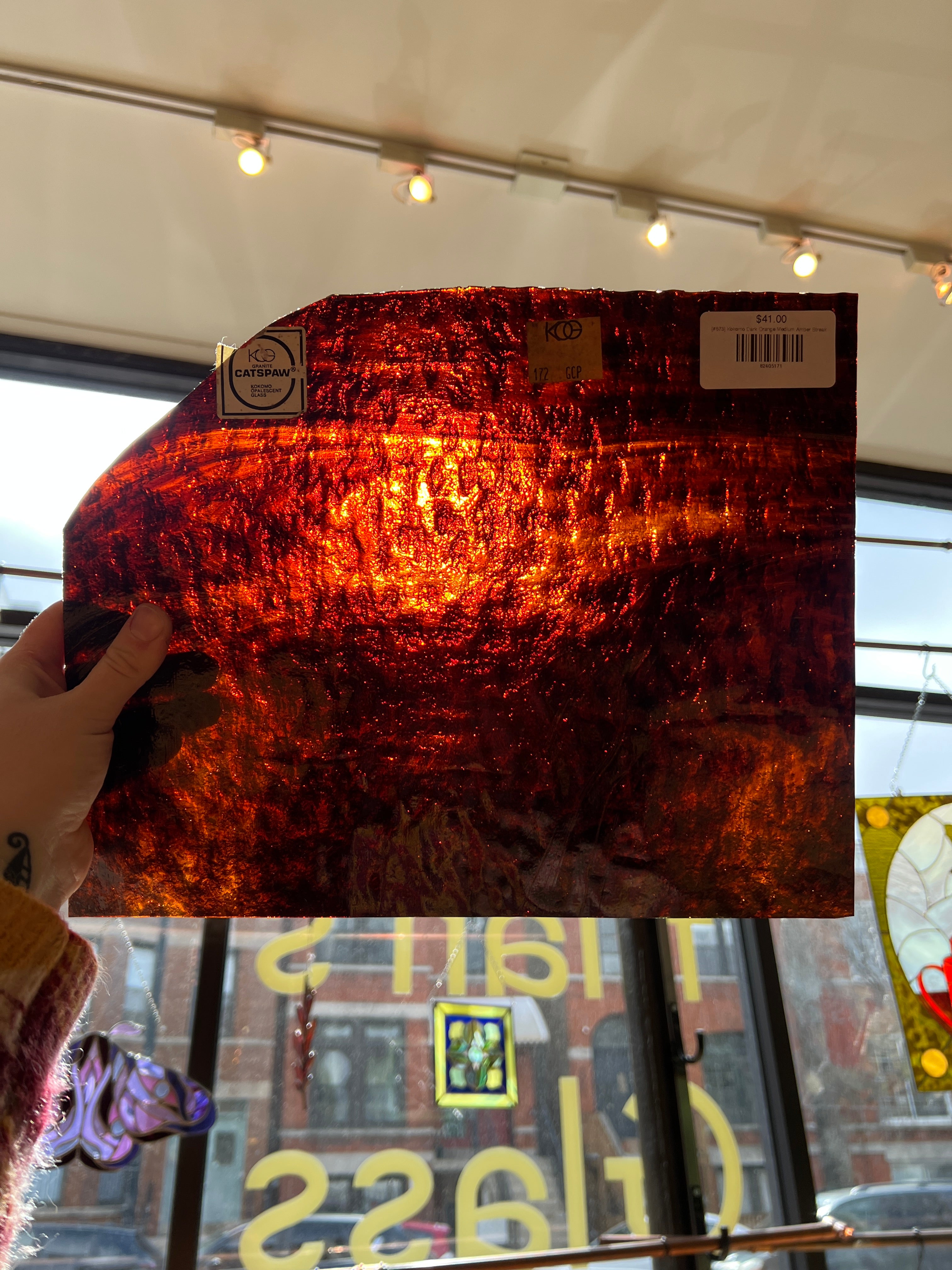 Person holding a textured orange piece of glass with a blurred background