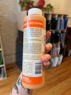 Hand holding a bottle of 'Dust Cleanup' cleaner with a blurred background