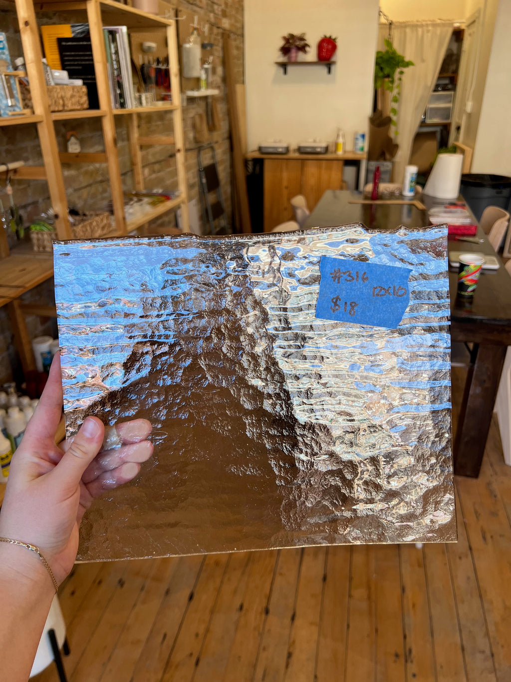Person holding a textured piece of glass in an indoor setting