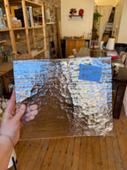Person holding a textured piece of glass in an indoor setting