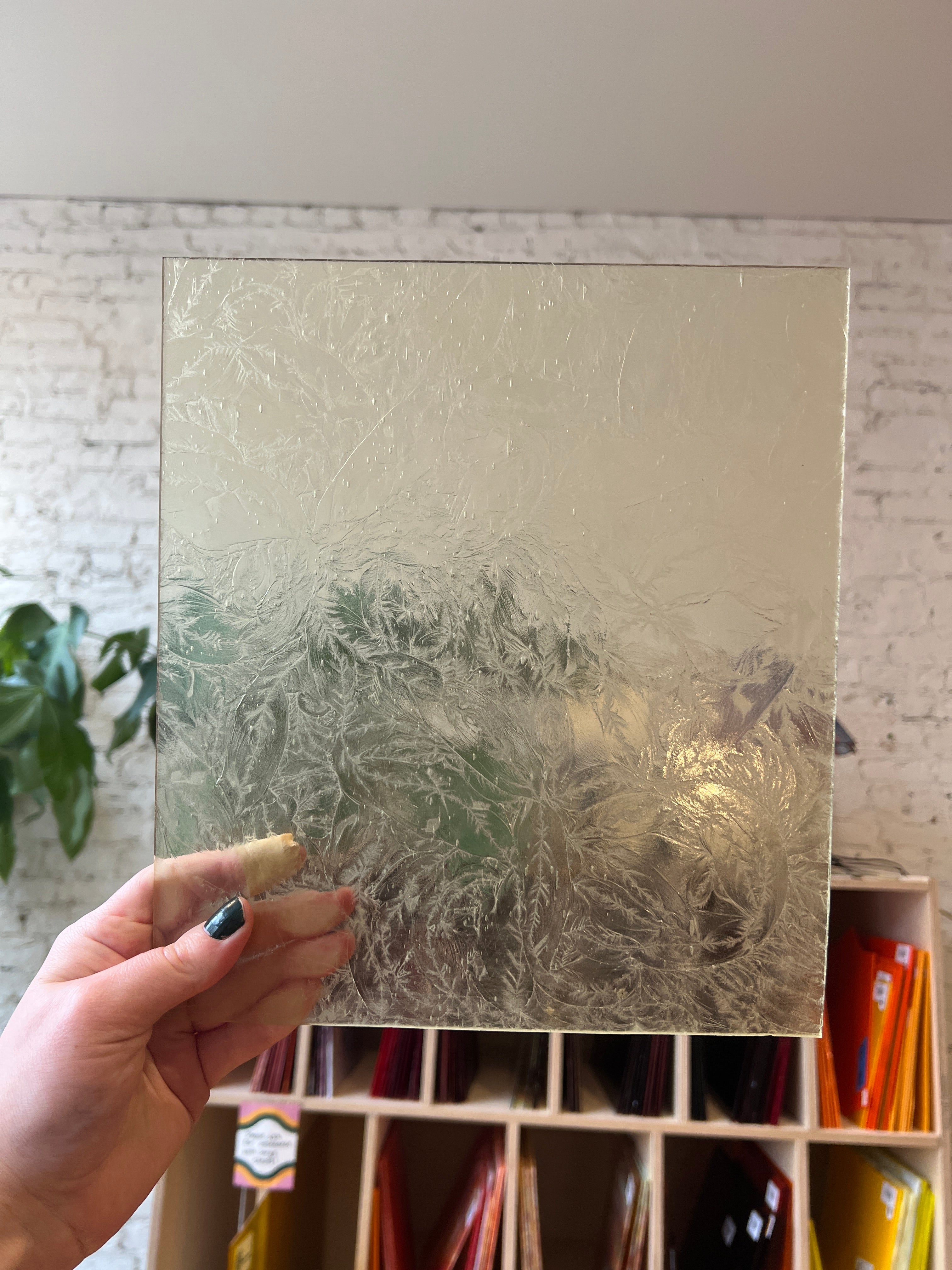 Hand holding a textured piece of stained glass with a blurred background