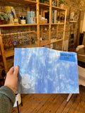 Person holding a blue mottled piece of glass a room with wooden shelves and decor.