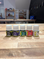 Set of small stained glass supply bottles on a wooden surface with a blurred indoor background
