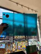 Blue textured piece of glass held by a hand with a stained glass window in the background
