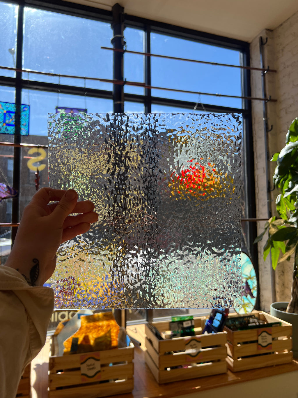 Hand touching a textured glass piece with a blurred outdoor view
