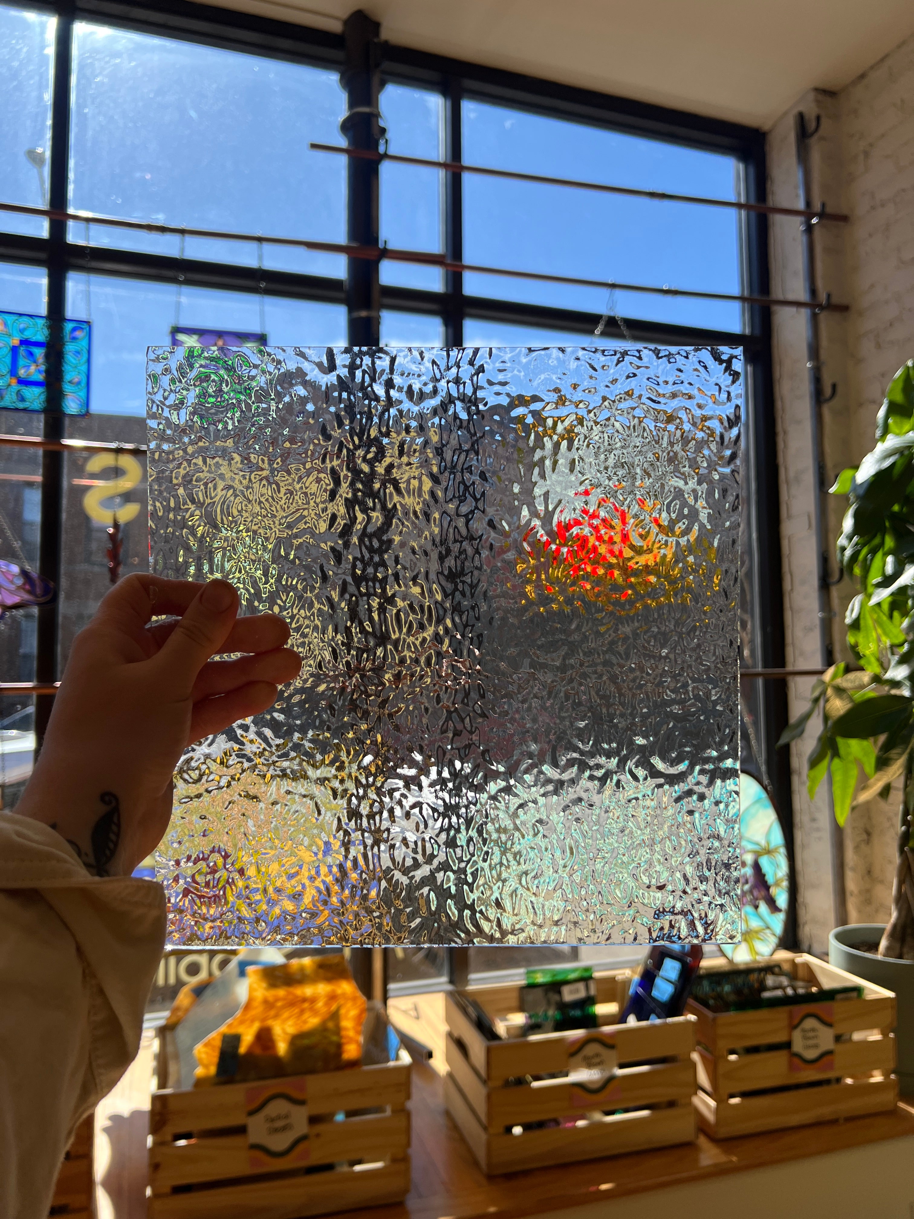 Hand touching a textured glass piece with a blurred outdoor view