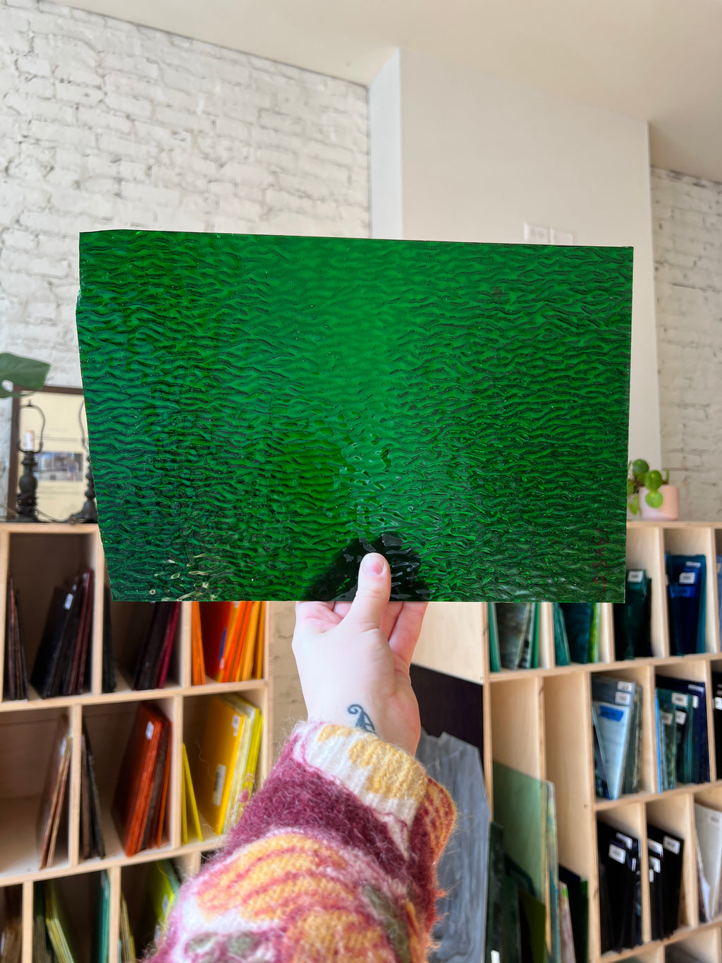 Green textured sheet of glass held by a person with a blurred background