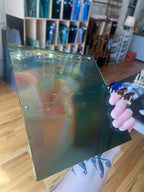 Person holding a transparent sheet of stained glass with a blurred indoor background