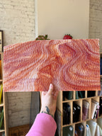 Block of marbled red and white glass held by a person with a pink sleeve.