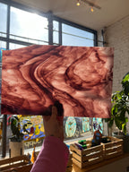 Person holding a large piece of stained glass with a swirling purple and white pattern in an indoor setting.