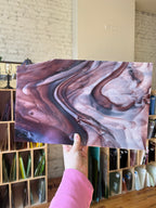 Person holding a piece of stained glass with dark purple and white swirls.