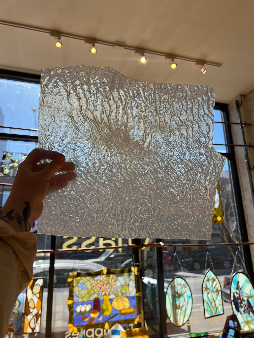 Textured transparent panel of glass held by a hand in front of stained glass windows