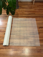 Roll of white mosaic mesh on a wooden floor with a plant in the corner
