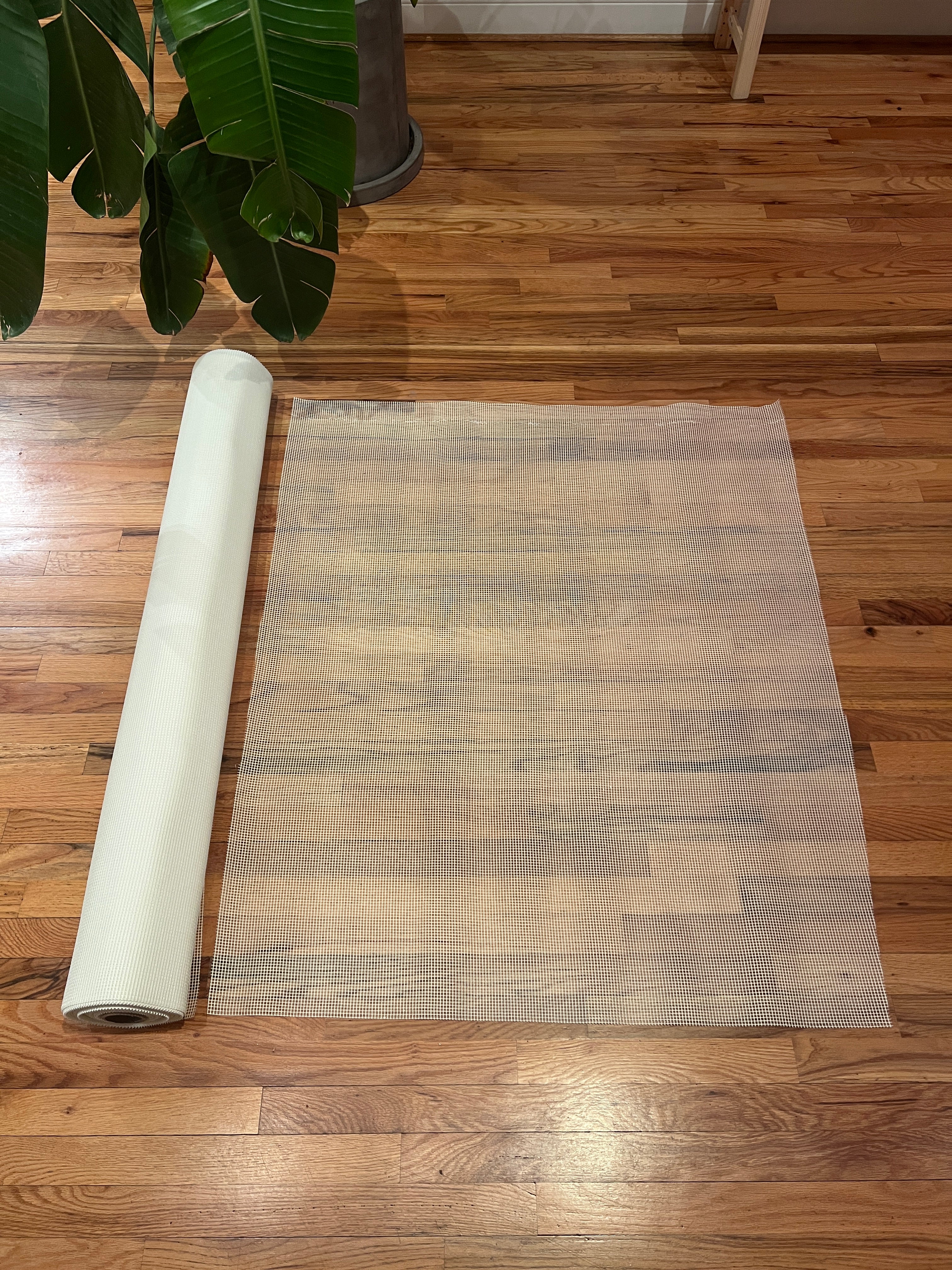 Roll of white mosaic mesh on a wooden floor with a plant in the corner