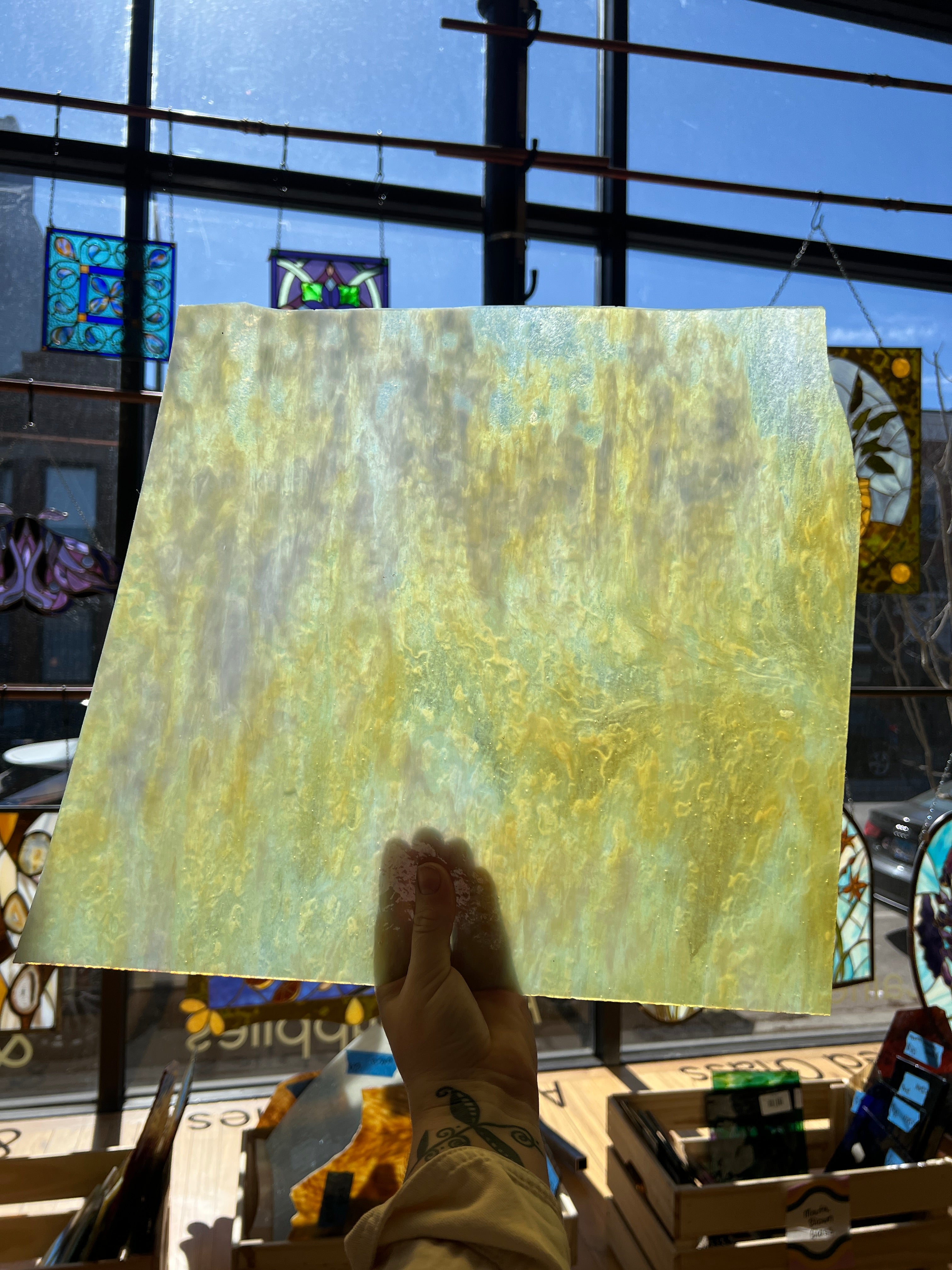 Yellow textured sheet of glass held by a person with a stained glass window in the background