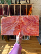 Person holding a piece of marbled and textured red and white stained glass