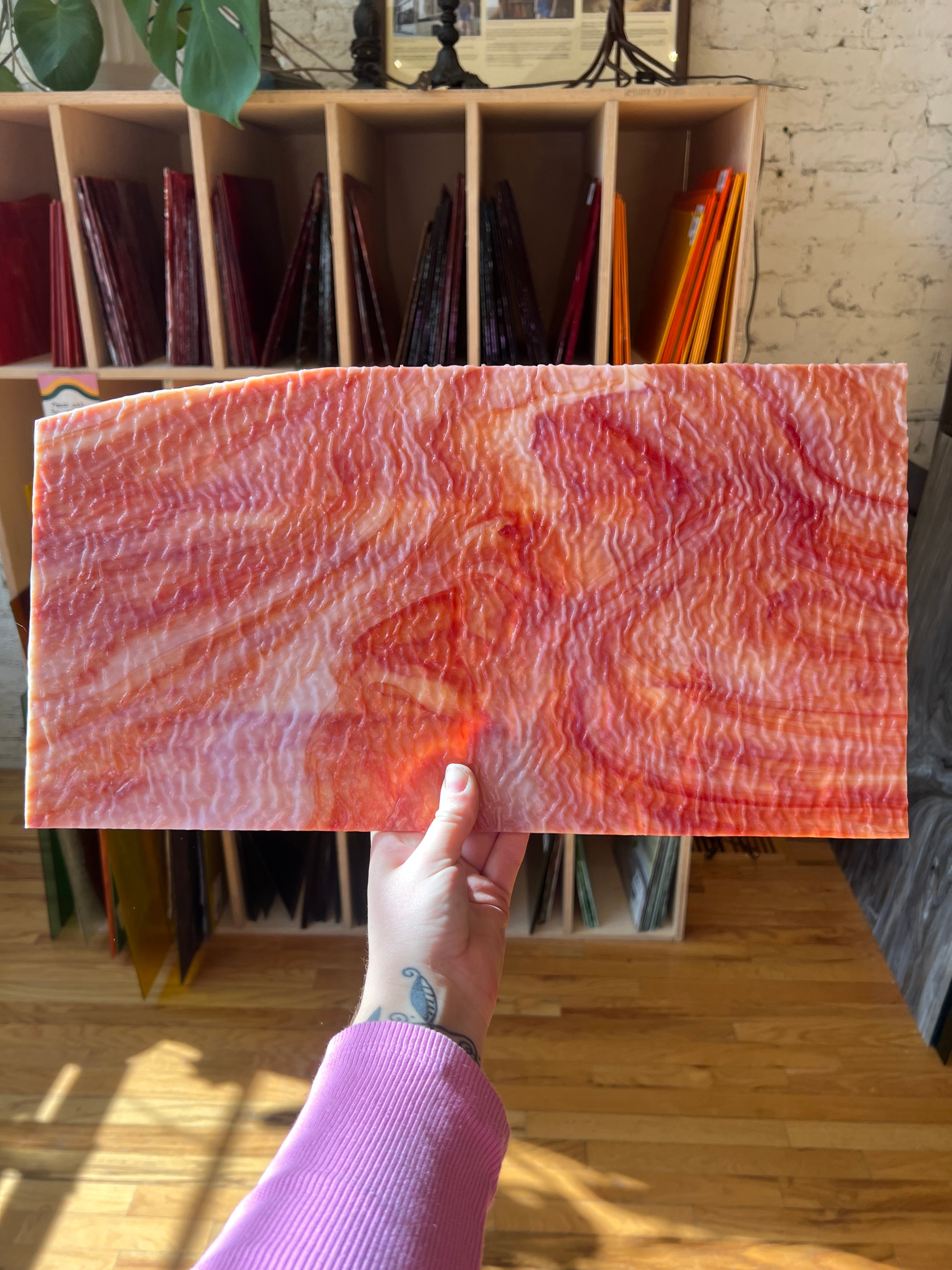 Person holding a piece of marbled and textured red and white stained glass