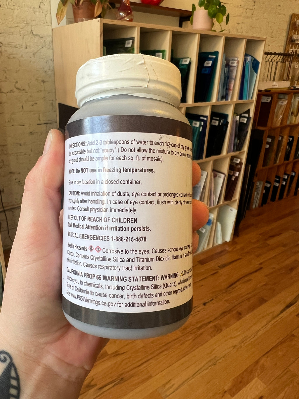 Hand holding a white container with text, blurred background