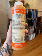 Hand holding a bottle of metal dust cleaner with a blurred background