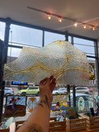 Hand holding a textured glass panel with artistic design in a store setting