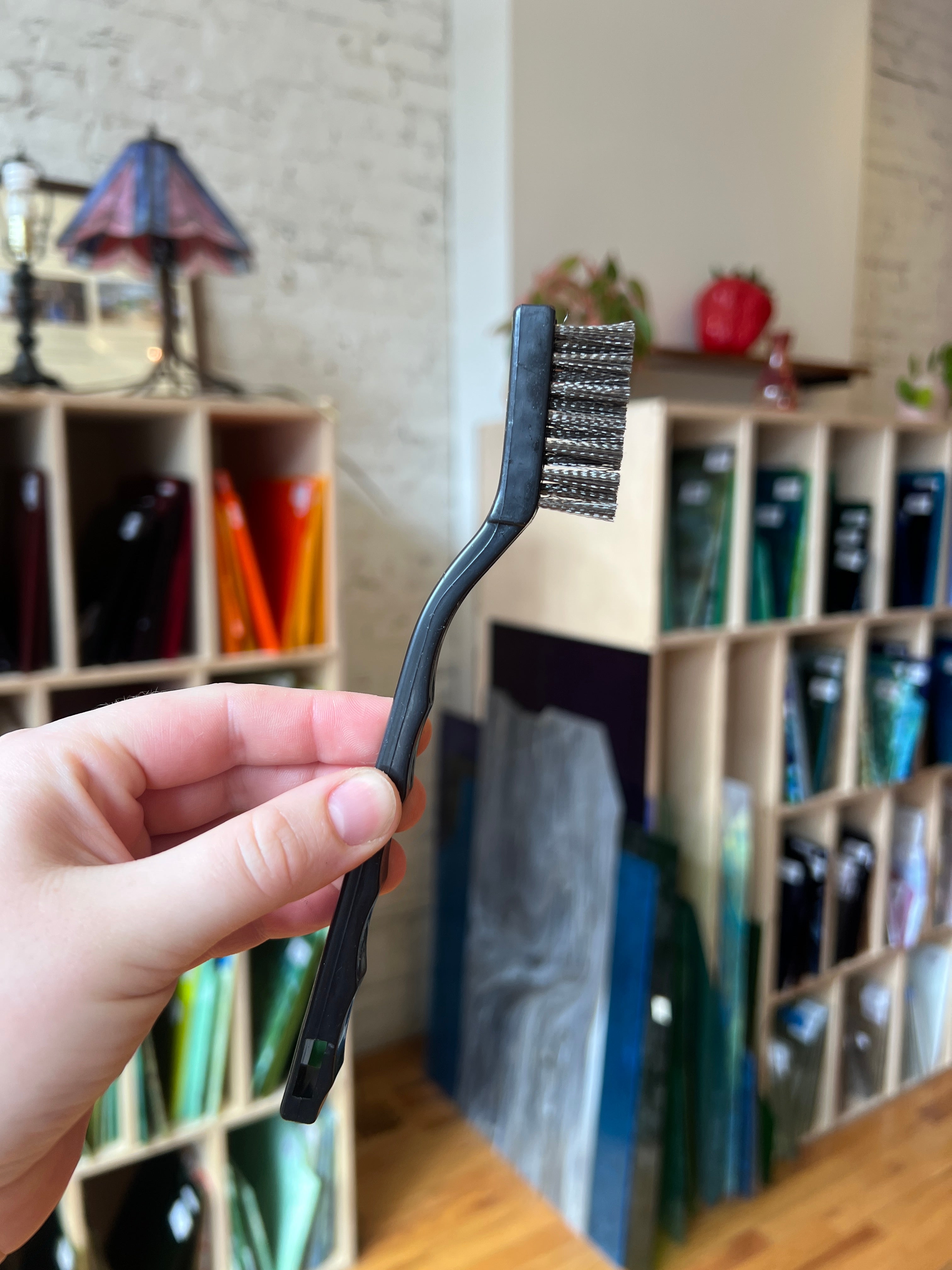 Hand holding a black wire brush with a blurred background