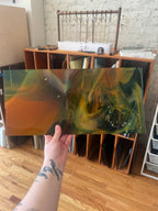 Person holding a swirled piece of stained glass with a blurred background of a room.