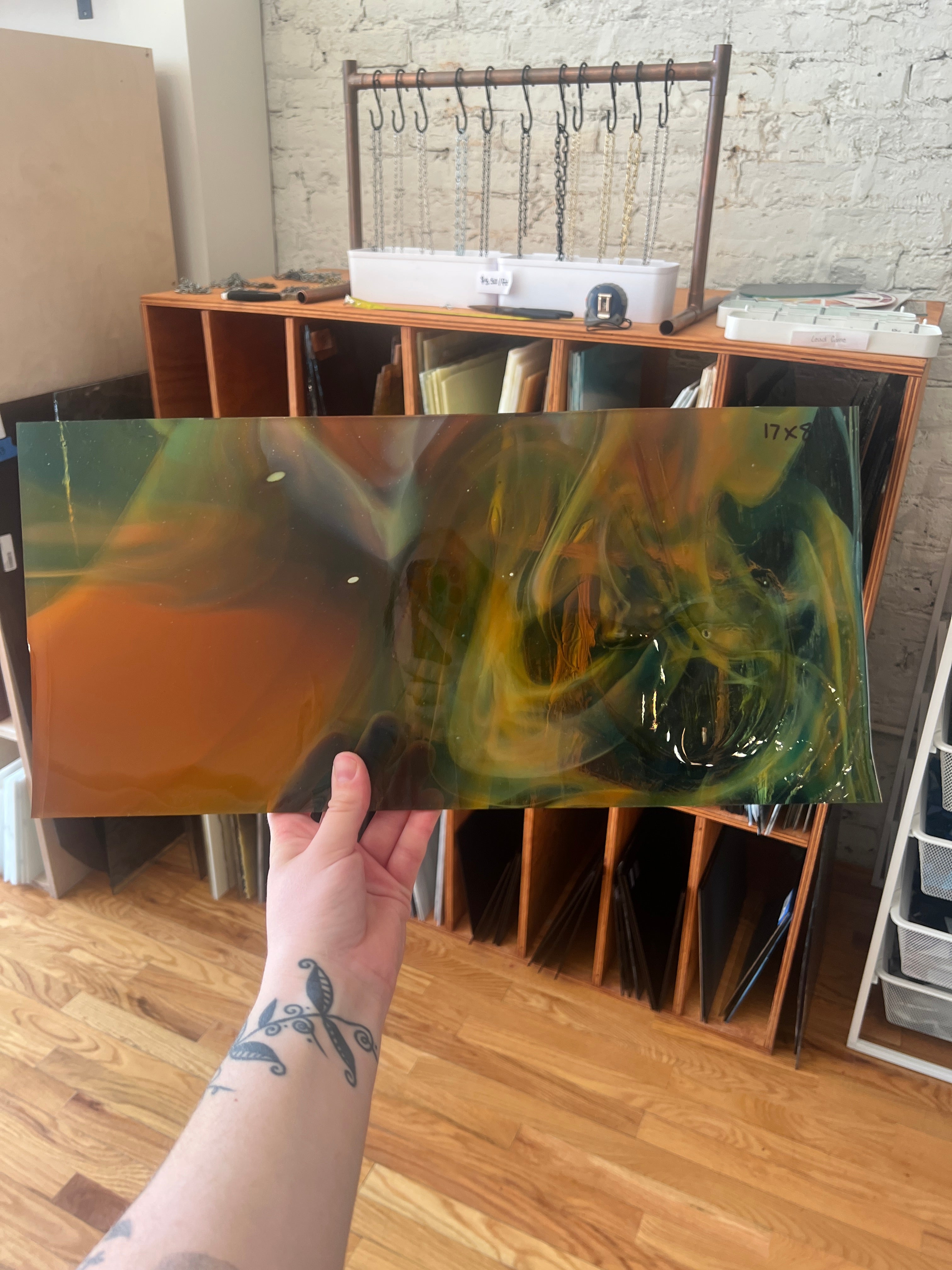 Person holding a swirled piece of stained glass with a blurred background of a room.