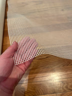Hand holding a piece of white mesh against a wooden surface
