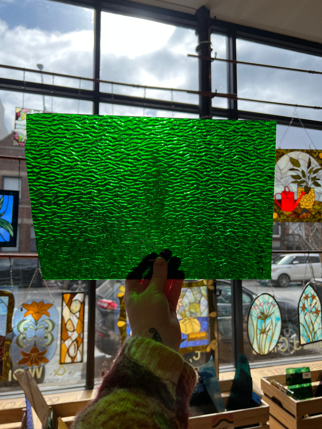 Green textured piece of stained glass in front of stained glass windows