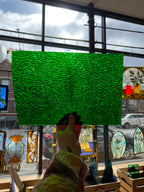 Green textured piece of stained glass in front of stained glass windows