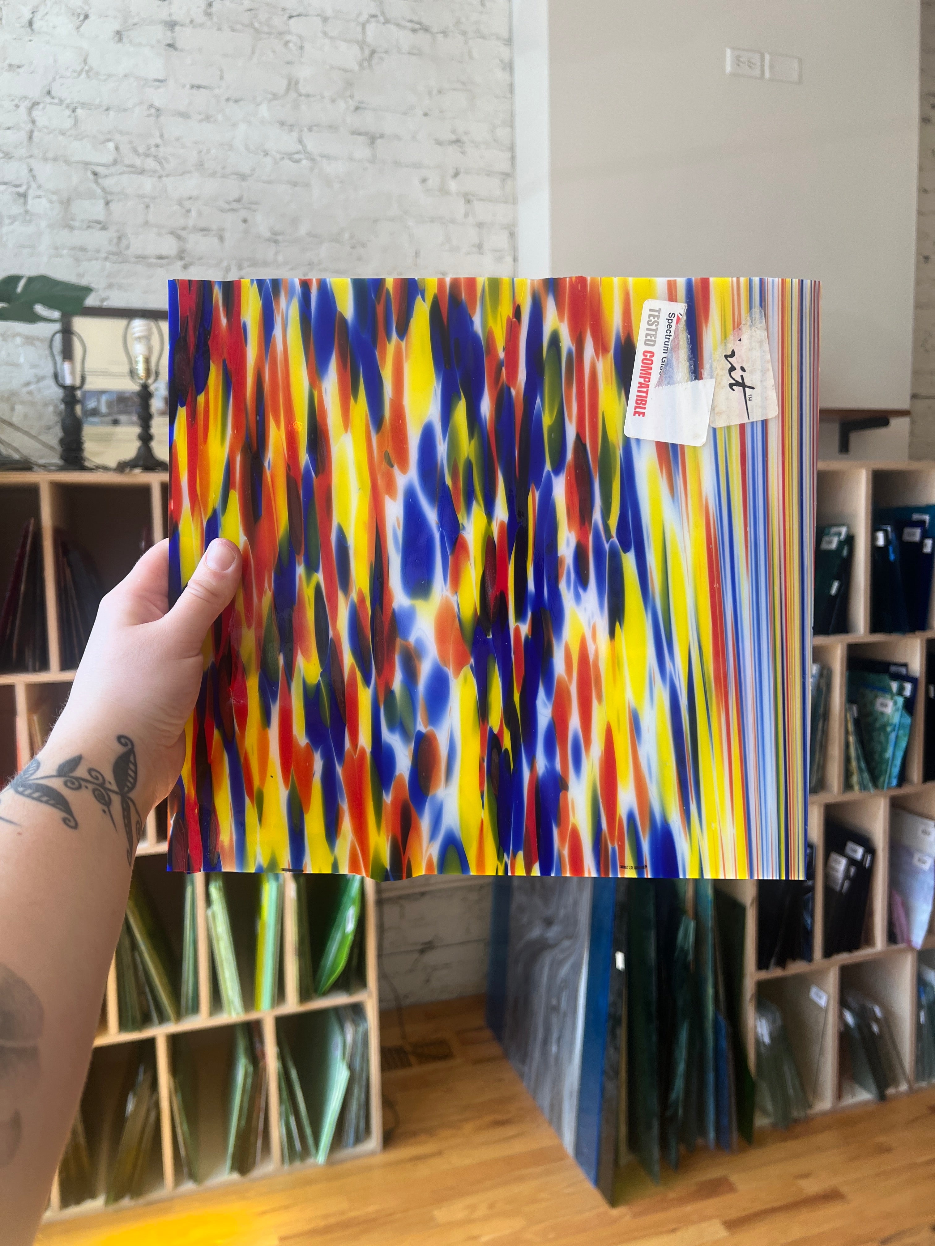 Colorful piece of stained glass held by a person in a store setting