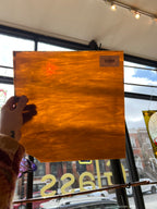 Piece of brown stained glass held by a hand with a blurred indoor background