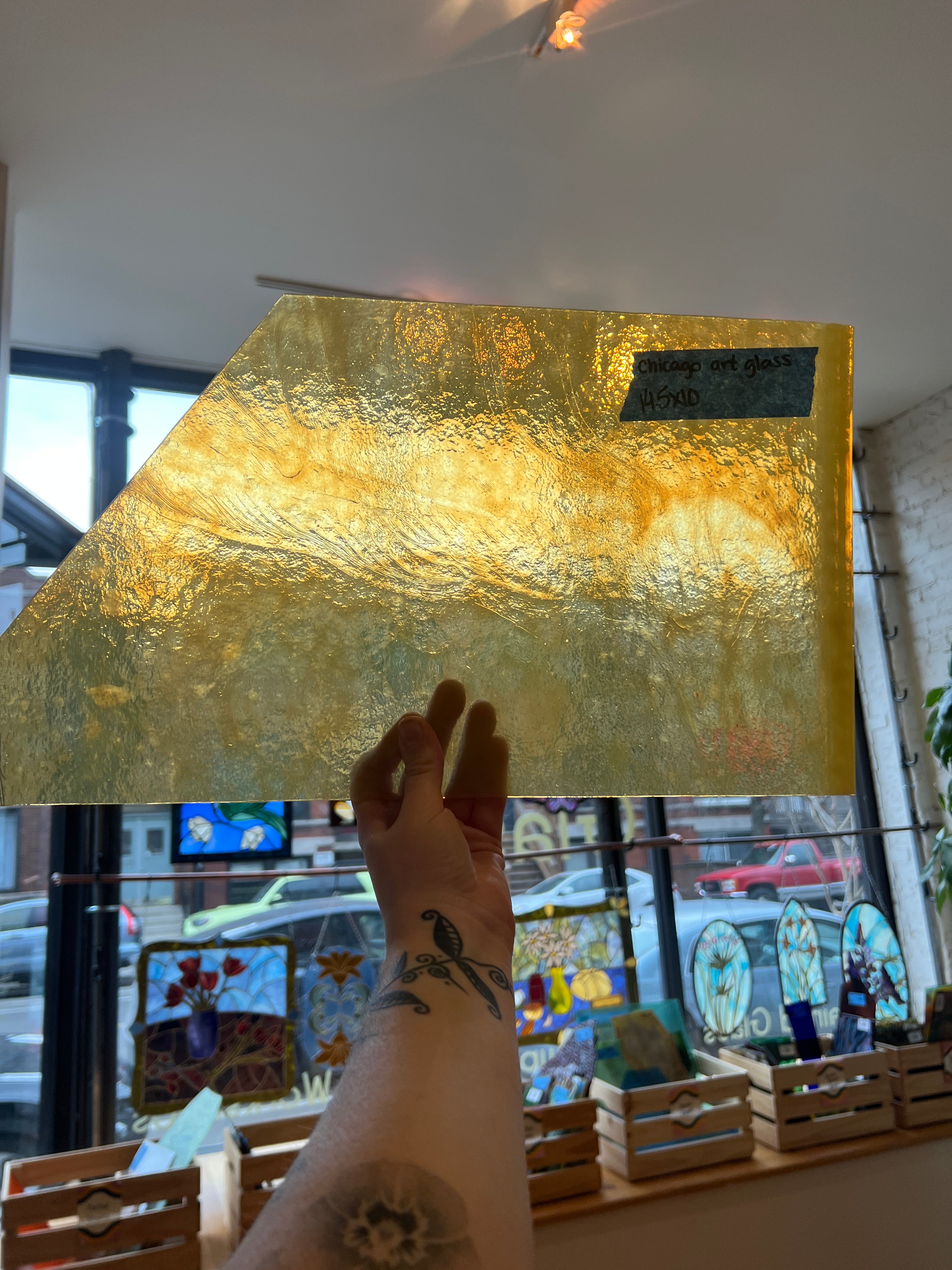 Gold textured sheet of stained glass held by a person with a blurred indoor background