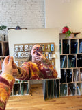 Person holding a mirror piece of stained glass with a blurred colorful background 