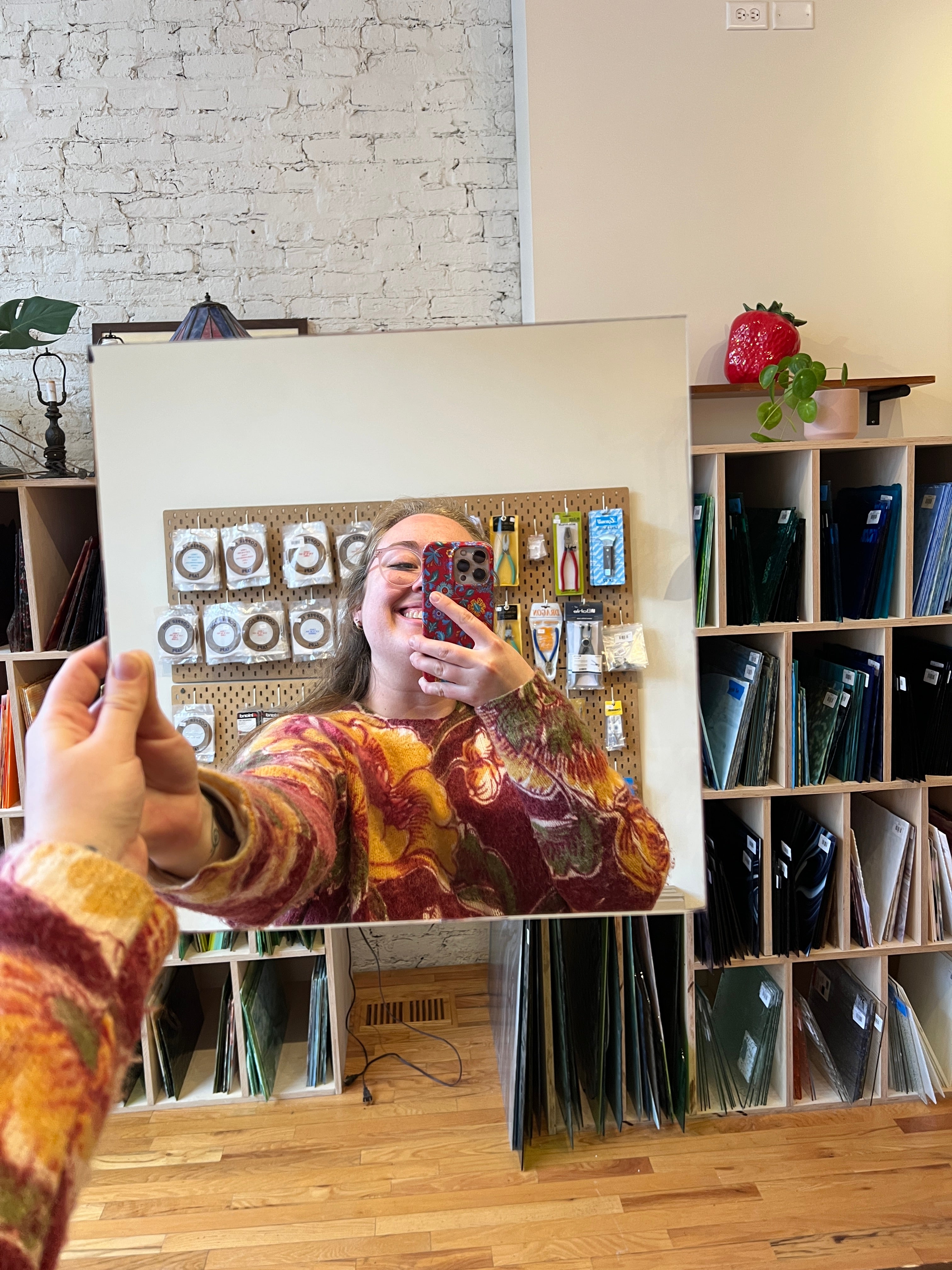Person holding a mirror piece of stained glass with a blurred colorful background 