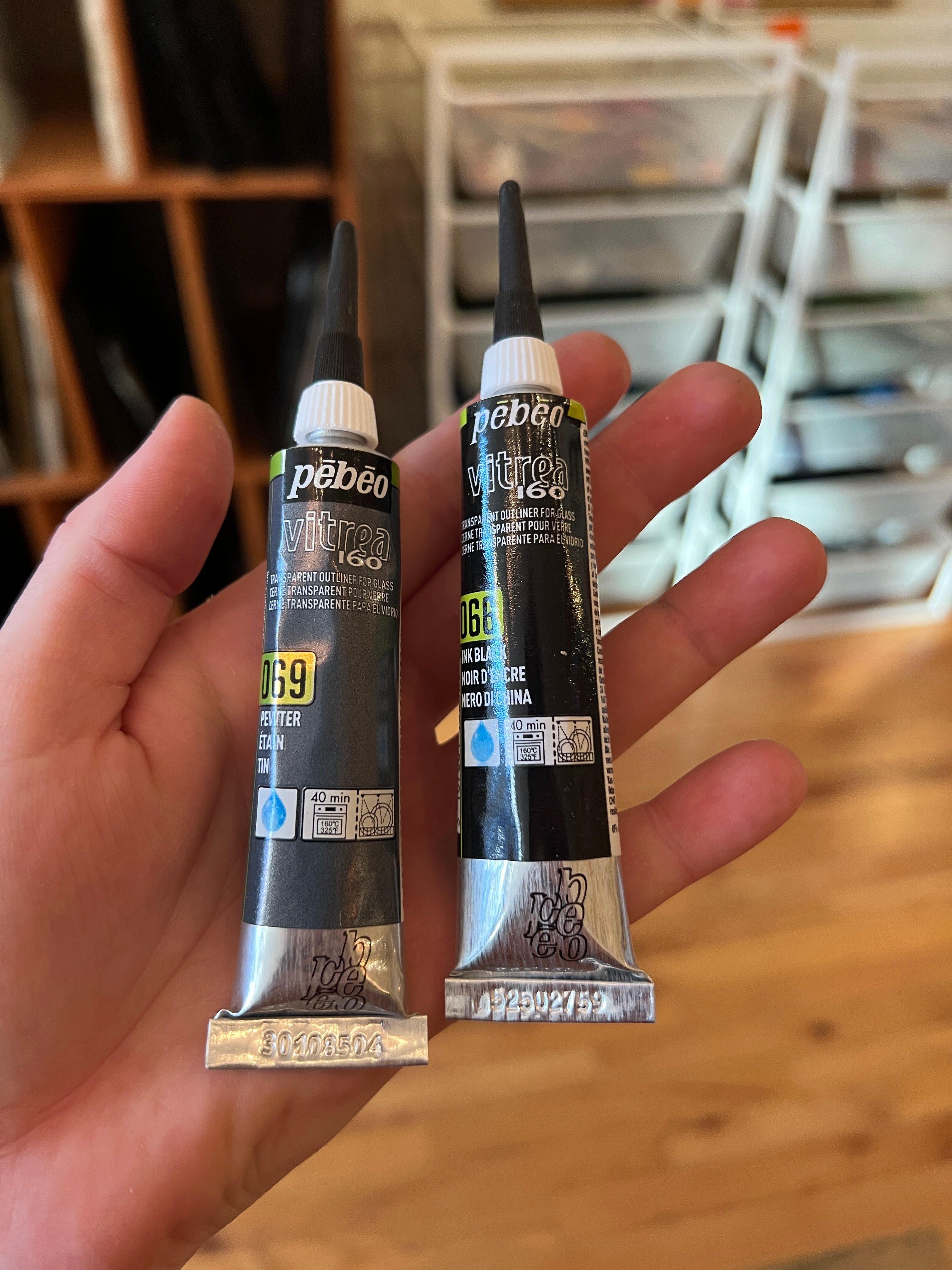 Two tubes of vitrea 160 held by a hand with a blurred indoor background