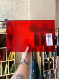 Red glass panel with a visible brand label held by a hand, with a collage of similar panels in the background.