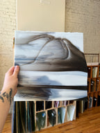 Person holding a piece of gray and white stained glass with a blurred background