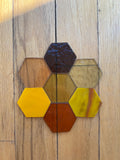 Hexagonal glass pieces in various yellow colors on a wooden surface