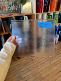 Person holding a textured glass panel with a blue label in a store setting