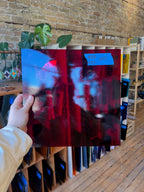 Person holding a reflective red glass sheet with blurred background