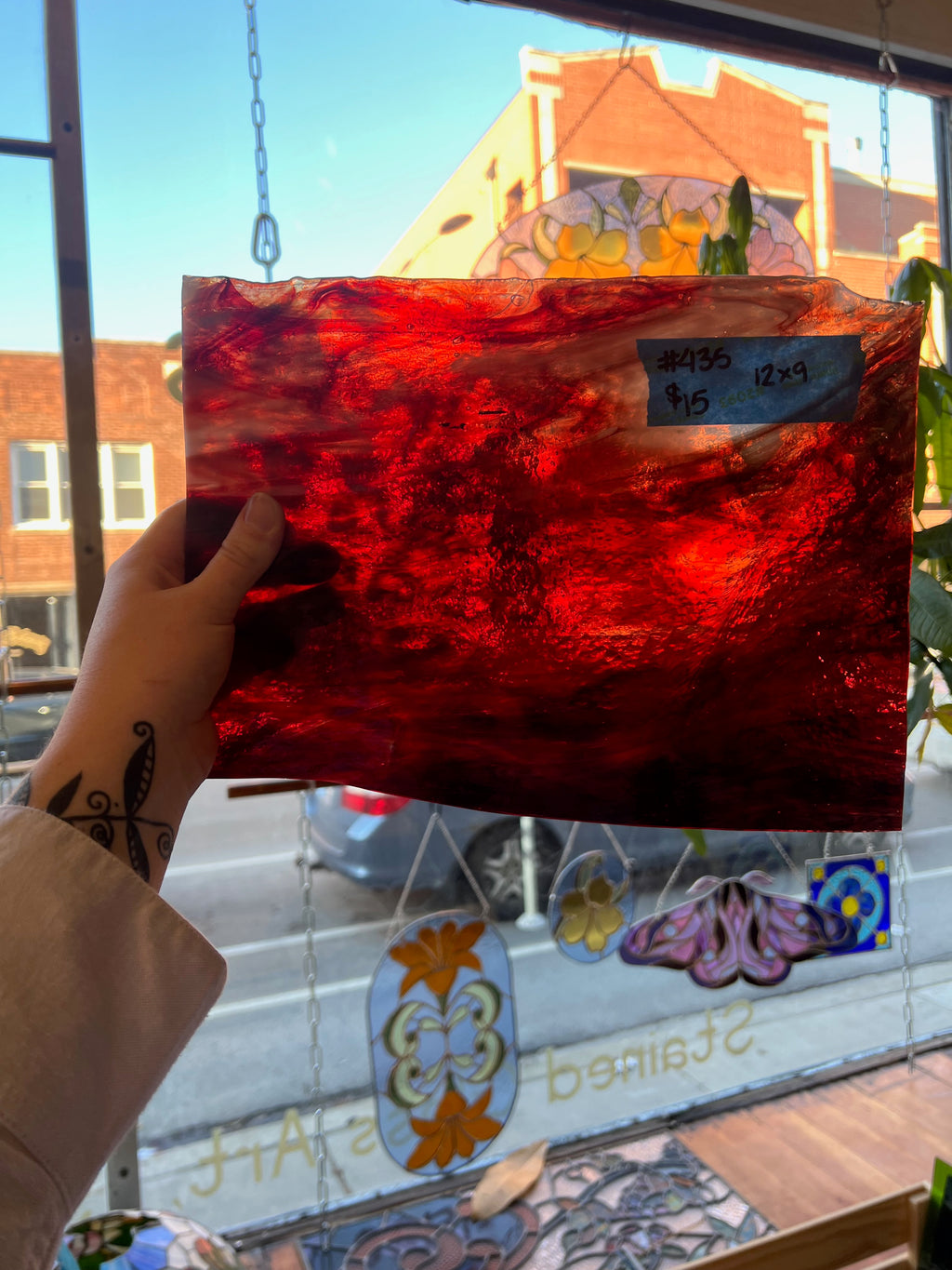 Red glass panel with a price tag held up in front of a window display.