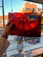 Red glass panel with a price tag held up in front of a window display.